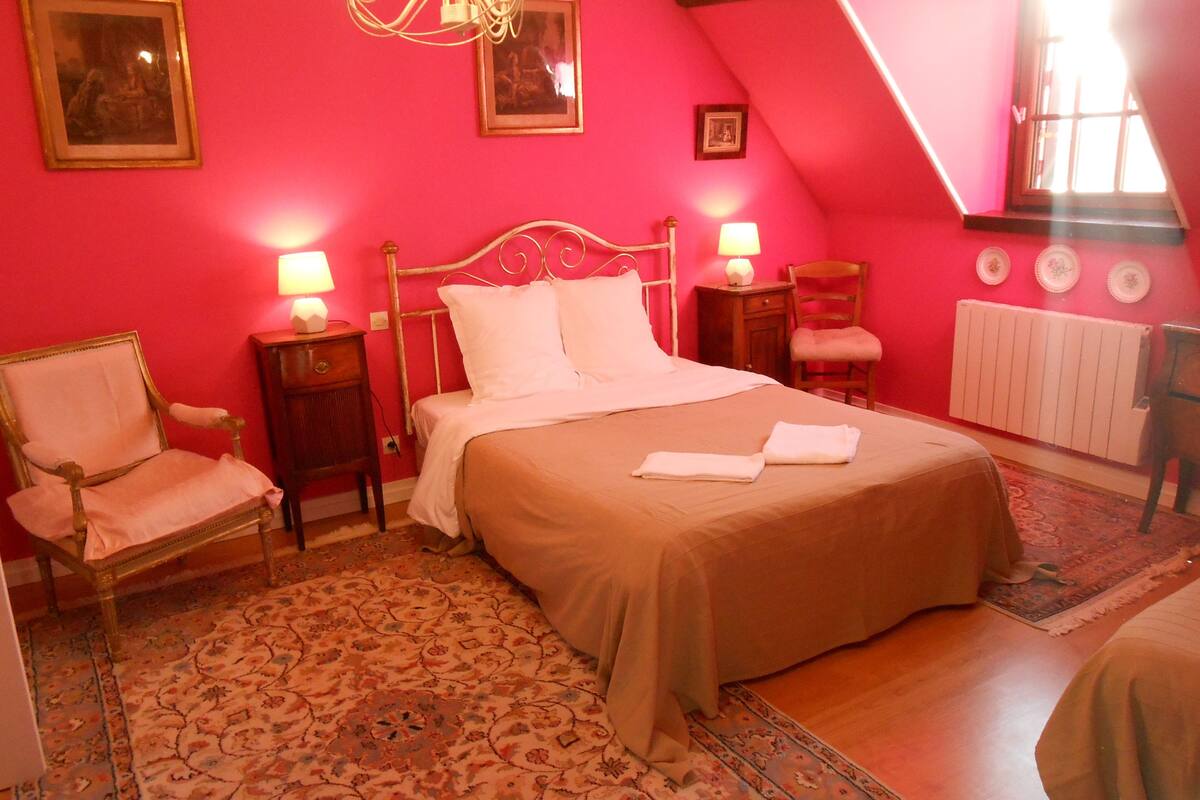 Un dormitorio con una cama grande, dos mesitas de noche con lámparas, una silla y un radiador.