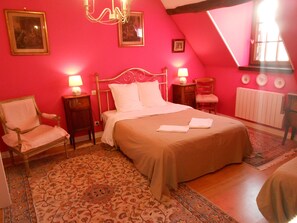 A bedroom with a large bed, two bedside tables with lamps, a chair, and a radiator. - B&B La Ferme Des Bordes (Pontlevoy)