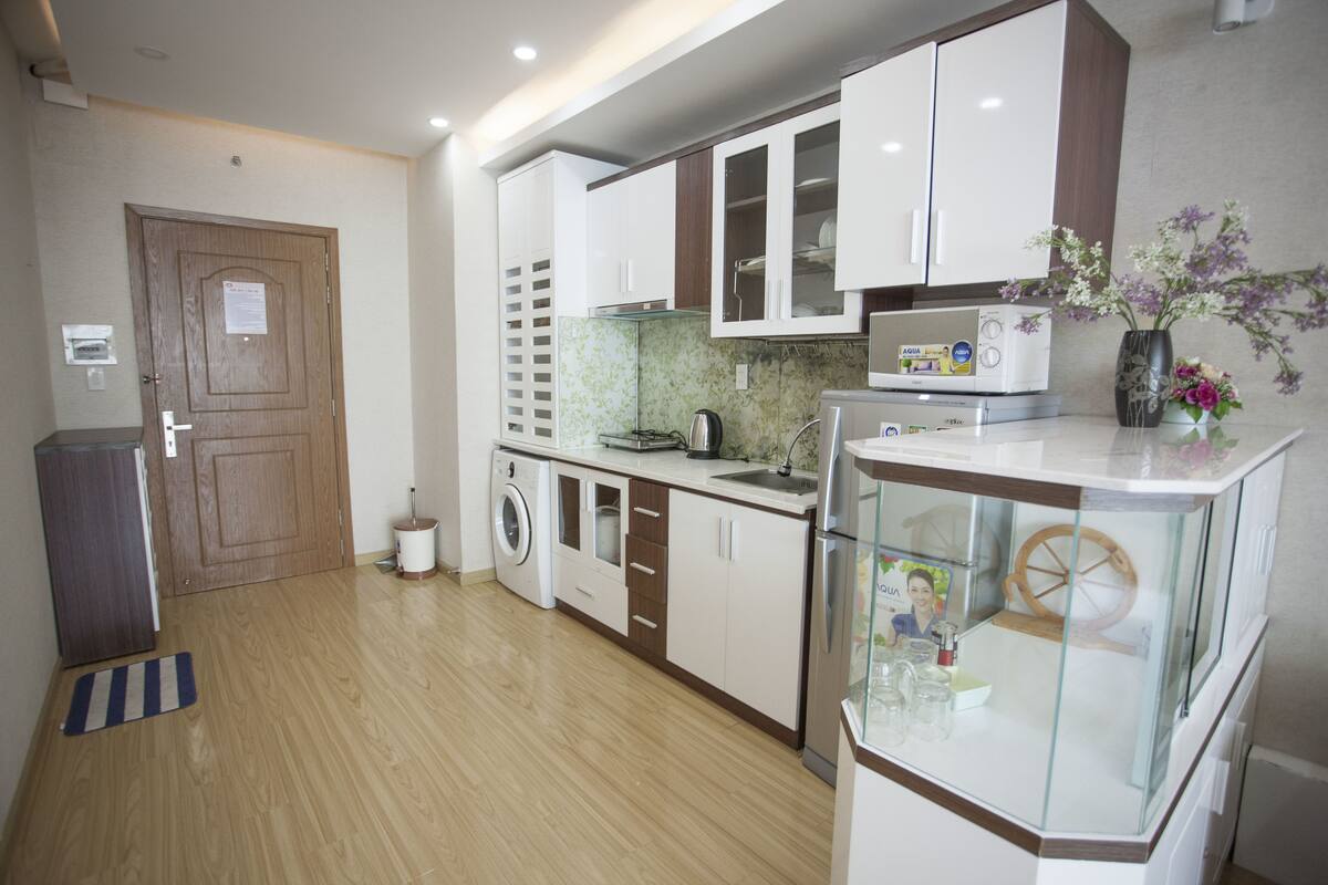A modern kitchen with white cabinets, a washing machine, and a glass display case.