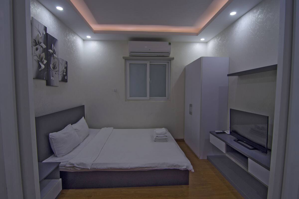 A modern bedroom with a bed, a TV, and an air conditioning unit.