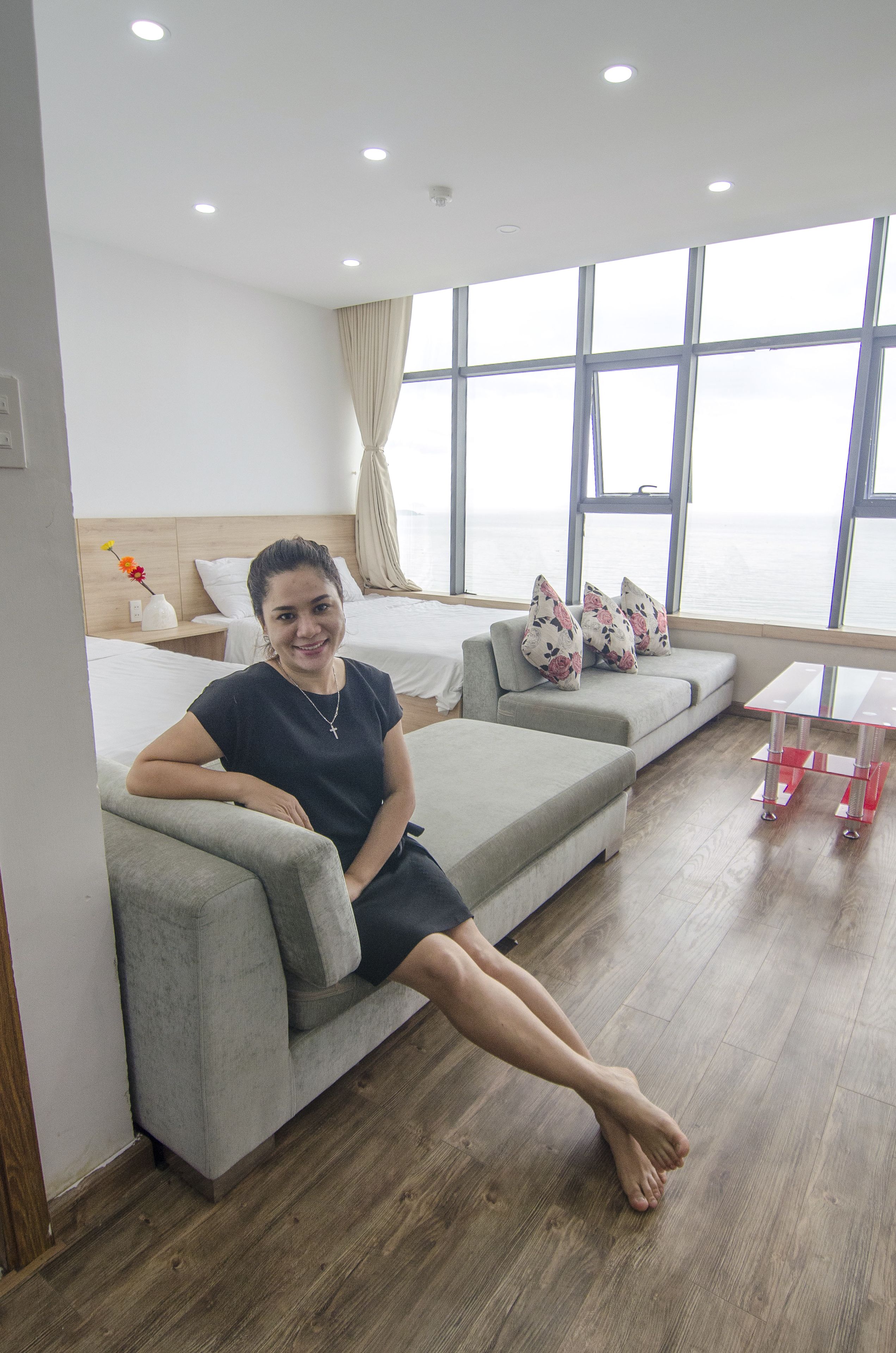 Een moderne hotelkamer met een groot raam, een bank, een bed en een tafeltje.