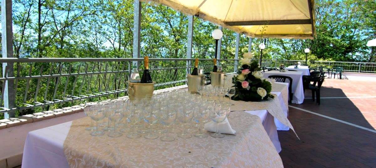Area pranzo all'aperto con tavoli apparecchiati, circondata da un parapetto e una tettoia.