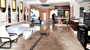 Un vestíbulo de hotel con mostrador de recepción, zona de estar y un diseño de piso con motivos de estrellas.