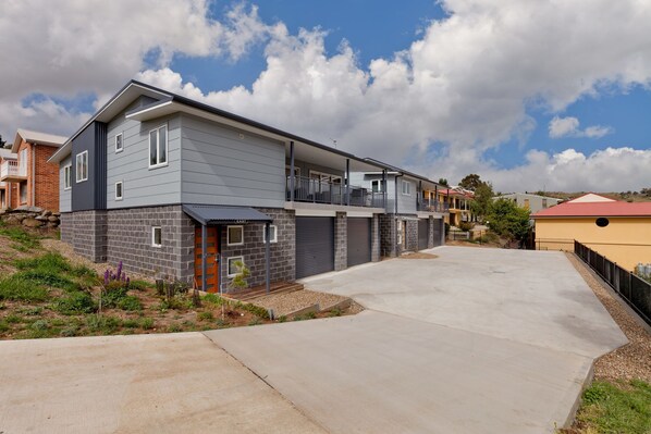 A modern two-story residential building with a grey exterior and a stone facade.