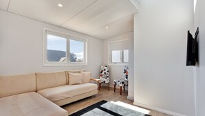 Uma sala de estar moderna com um sofá bege, um tapete preto e branco e duas cadeiras com estampas florais.