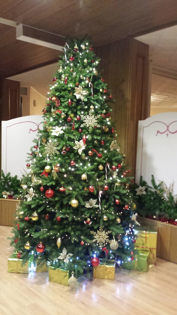A Christmas tree with ornaments and lights, surrounded by gift boxes. - Hotel Club Funivia (Corteno Golgi)