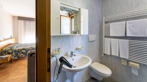 Ein Hotelzimmer mit Bett, Bad mit Waschbecken, Toilette und Handtuchhalter.