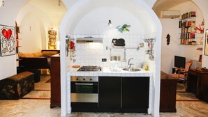 A compact kitchen with a central island, built-in oven, and a sink. There are bookshelves and a television in the adjacent living area. - Caio Mario (Rome)