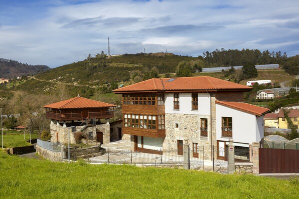 A two-story house with a red-tiled roof, stone walls, and a balcony. - Casa Josefa (Candamo)
