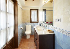 A bathroom with a toilet, sink, and mirror. - Casa Josefa (Candamo)