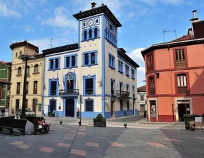 A historic building with a clock tower, a central entrance, and a surrounding plaza with benches. - Casa Josefa (Candamo)