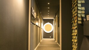 A hallway with a circular light fixture, a wall-mounted light, and a vertical strip of notes.