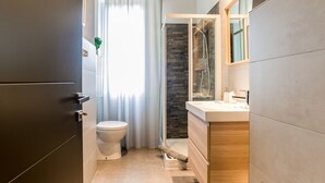A modern bathroom with a toilet, shower, and vanity.