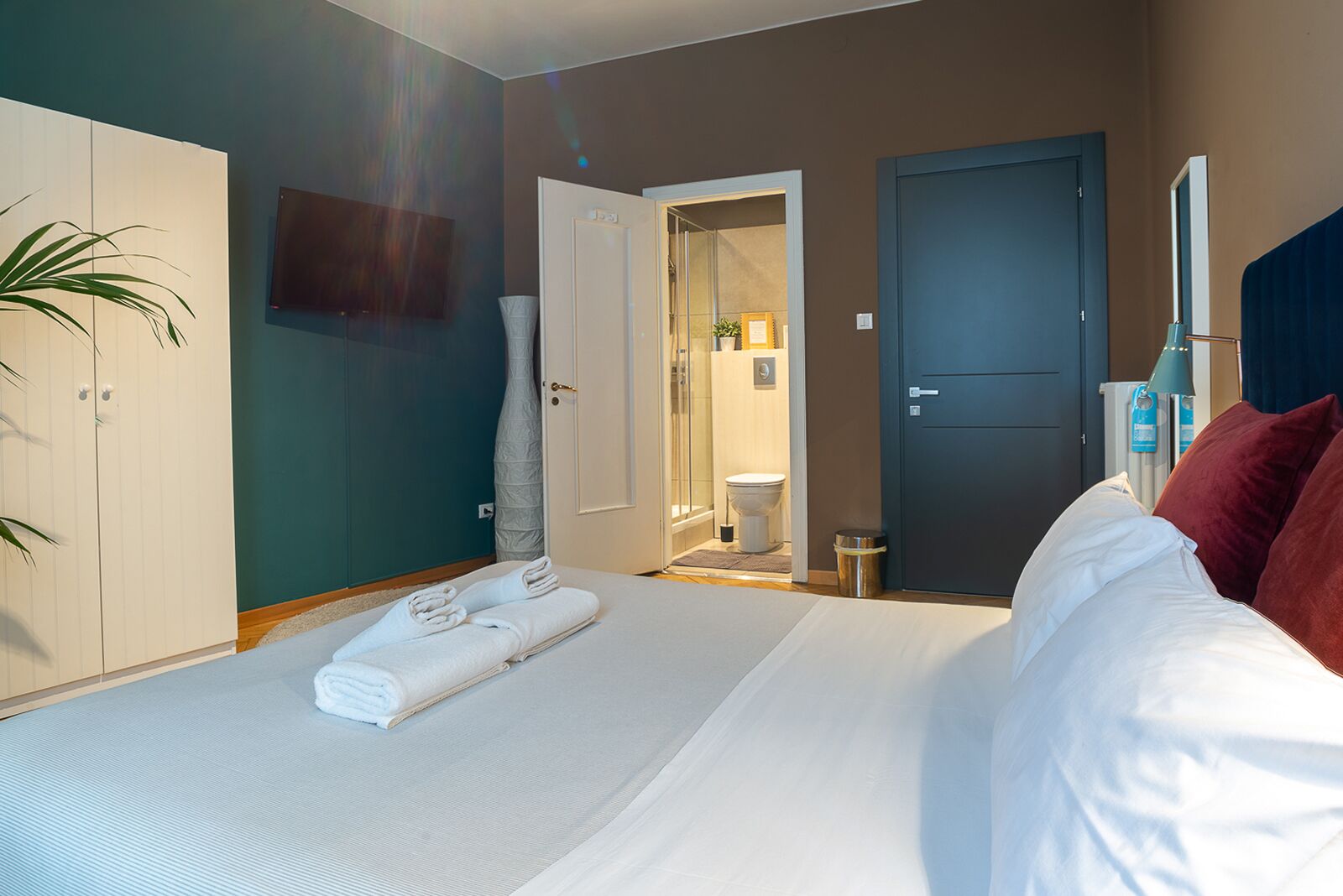 A hotel room with a bed, a wardrobe, a bathroom, and a TV.