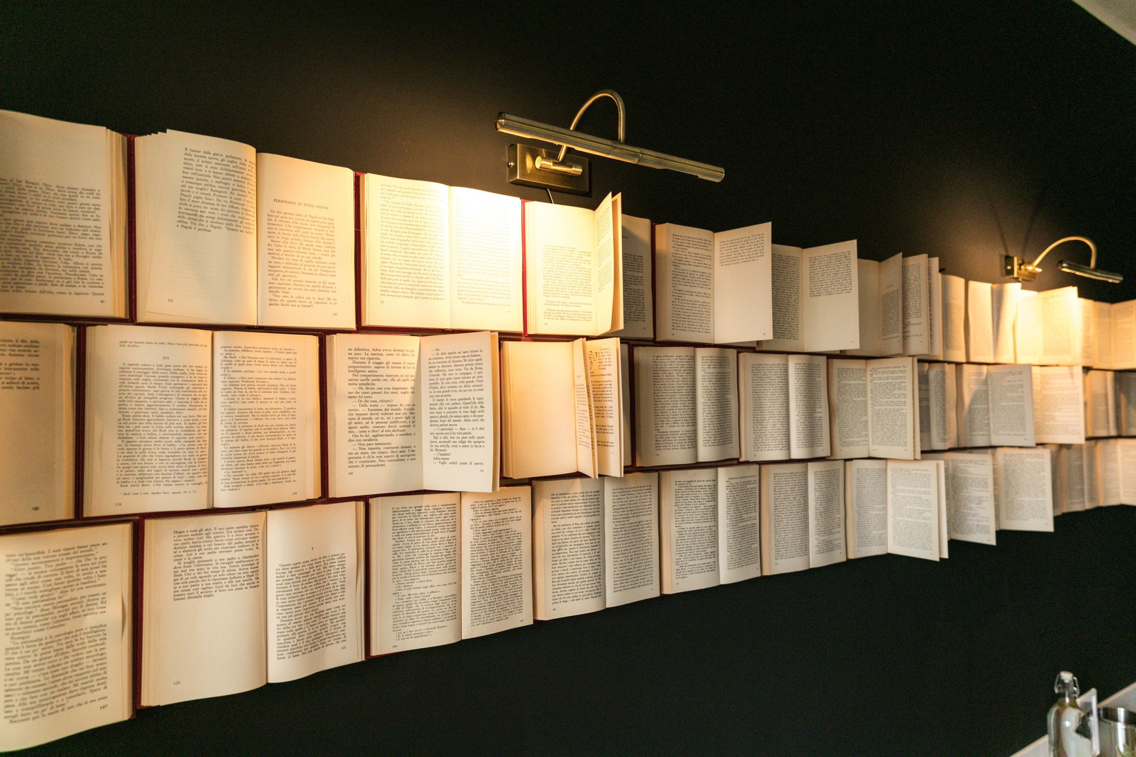A wall of open books with reading lights, arranged in a continuous row.