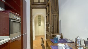 A kitchen with a built-in oven, a dining table with chairs, and a coffee station. - Gianicolo's Hill Suite Apartment (Rome)