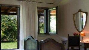 Une chambre à coucher avec un lit, une chaise, un bureau avec une lampe et une fenêtre avec des rideaux.