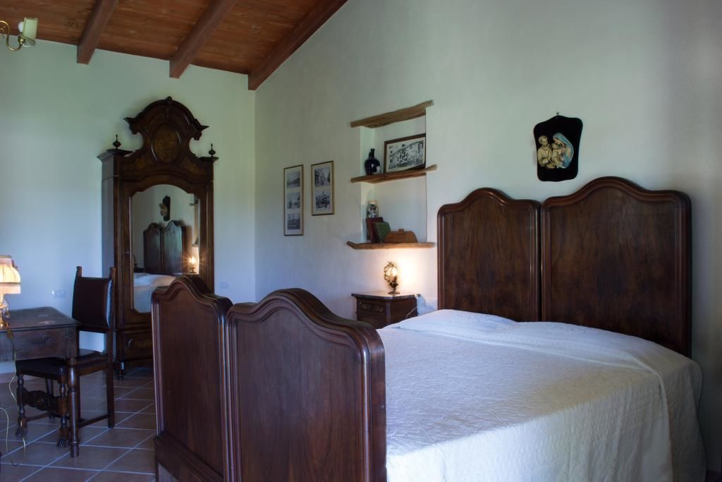 Une chambre à coucher avec un lit en bois, un bureau et une chaise. Des étagères murales sont fixées au mur et accueillent des objets décoratifs.