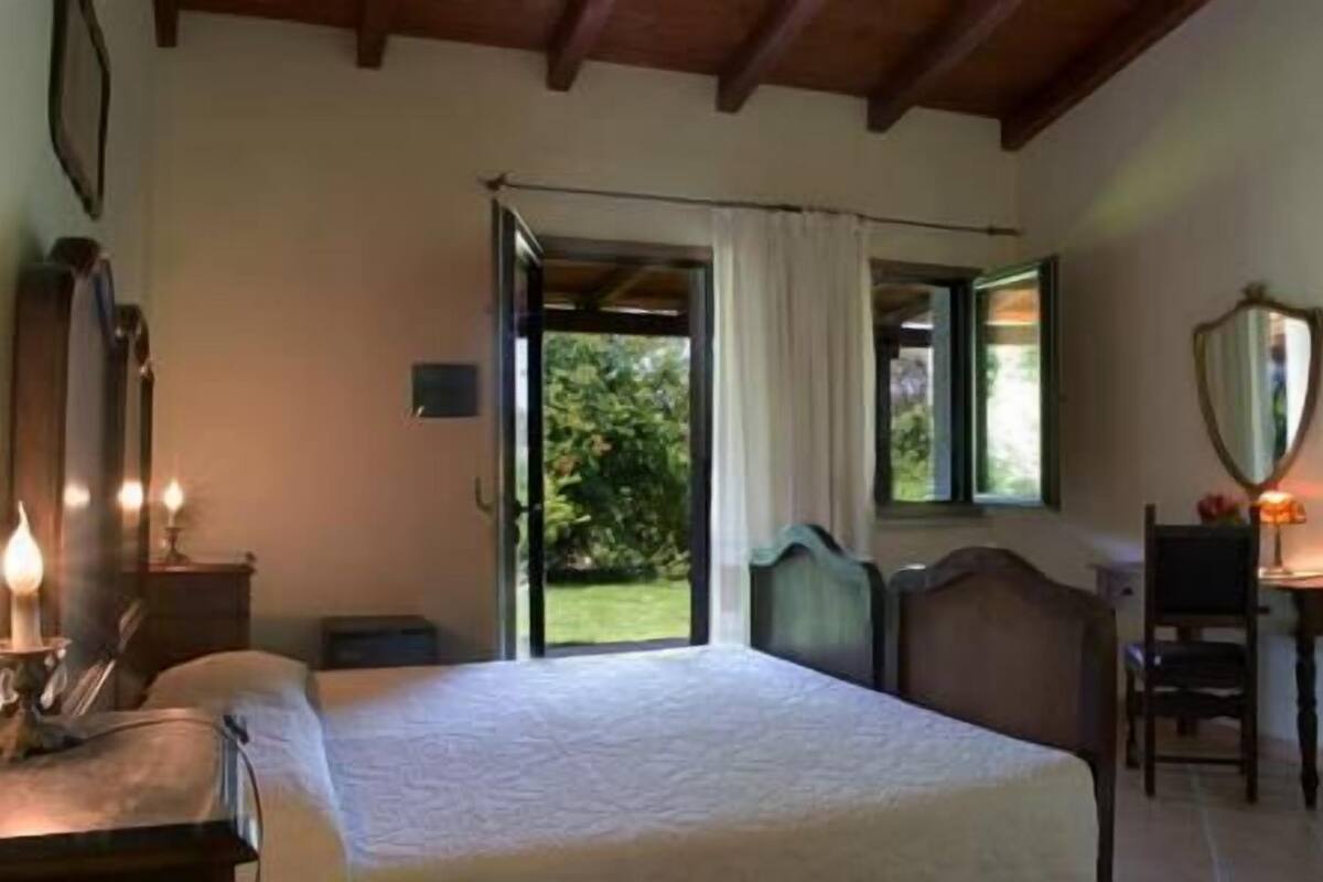 Ein Schlafzimmer mit Bett, Schreibtisch, Stuhl und einem fenster mit Vorhängen.
