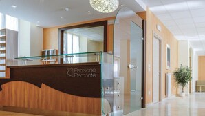 A reception desk with a glass top and a wooden base, labeled "Pensione Piemonte." - Pensione Piemonte (Loreto)