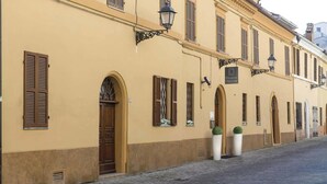A historic building with arched doorways and windows, a cobblestone street, and a sign indicating a pensione. - Pensione Piemonte (Loreto)