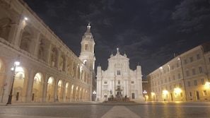A historic square with a prominent church featuring a bell tower and a central dome, surrounded by classical architecture.