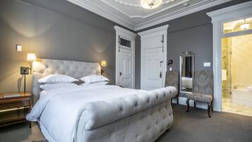 A bedroom with a large bed, two nightstands, a chair, and a mirror.