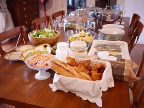 Una mesa de comedor dispuesta con diversos alimentos, como pan, frutas y salsas.