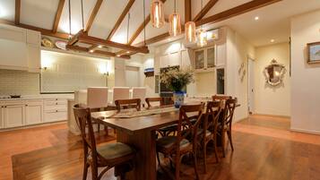 A spacious kitchen with wooden cabinets, a dining table with chairs, and pendant lights.