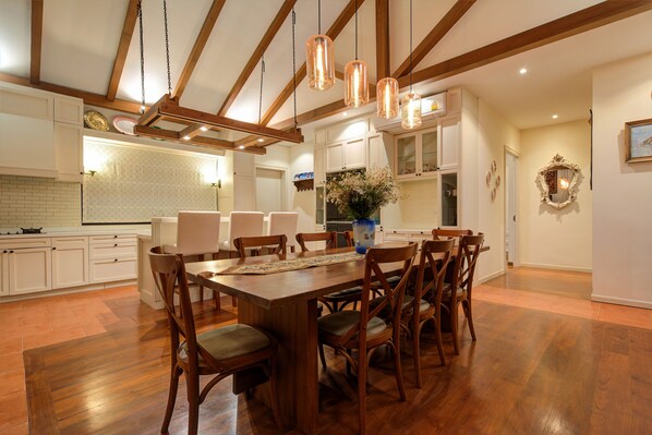 Una cocina amplia con gabinetes de madera, una mesa de comedor con sillas e iluminación colgante.