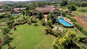 Una amplia casa con piscina, rodeada de exuberante vegetación y un césped cuidado.
