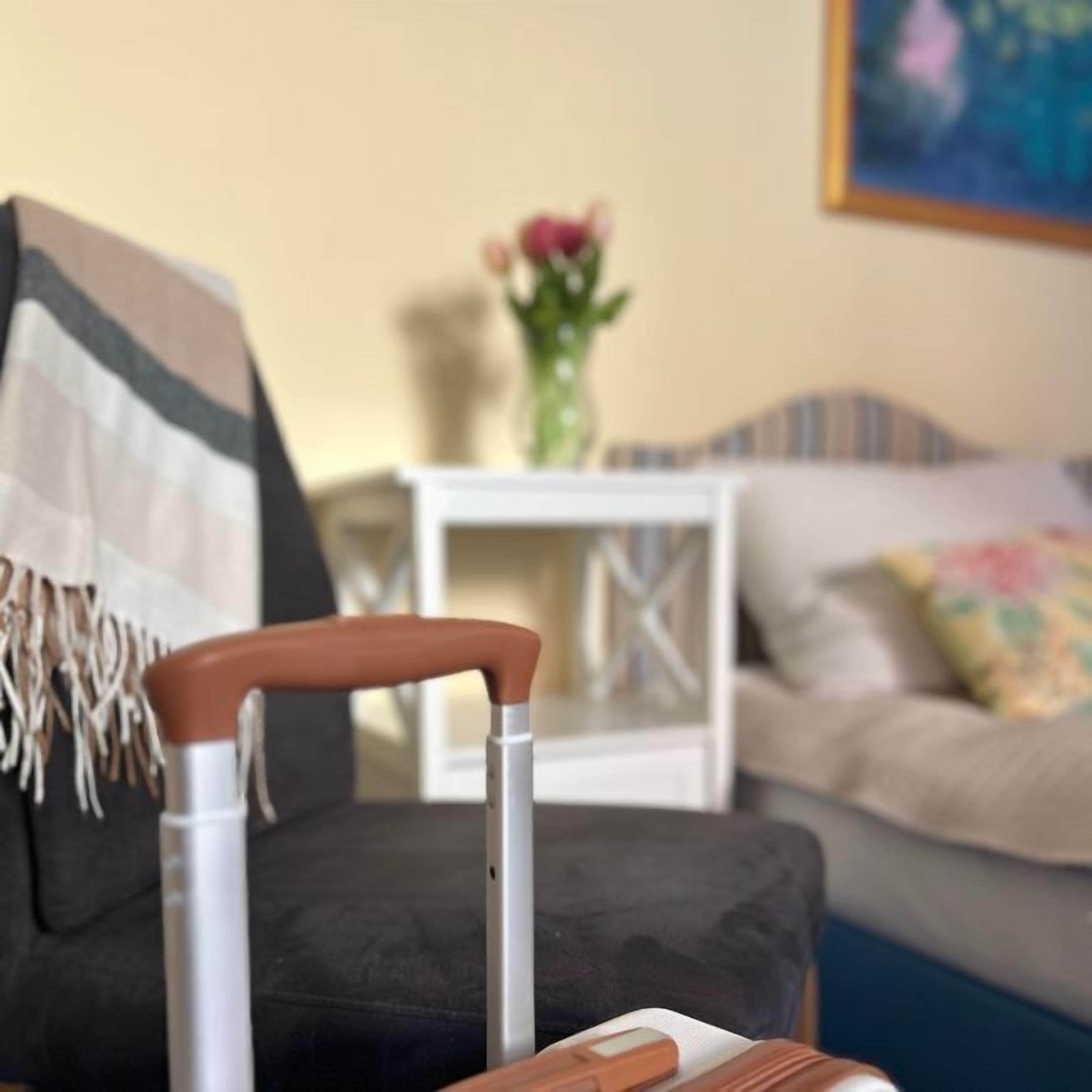 Une pièce avec un canapé gris, une table d’appoint blanche ornée d’un vase de fleurs et un fauteuil gris avec un accoudoir blanc.
