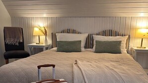 A neatly made bed with a suitcase, a chair, and two bedside tables with lamps. - Hotel Finkenhof - Haus Meersmannufer (Hannover)