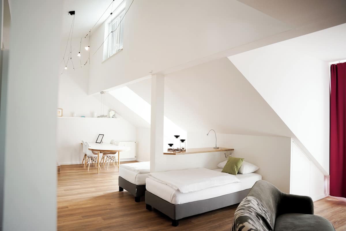 A modern loft bedroom with a loft bed, a desk, and a dining area.