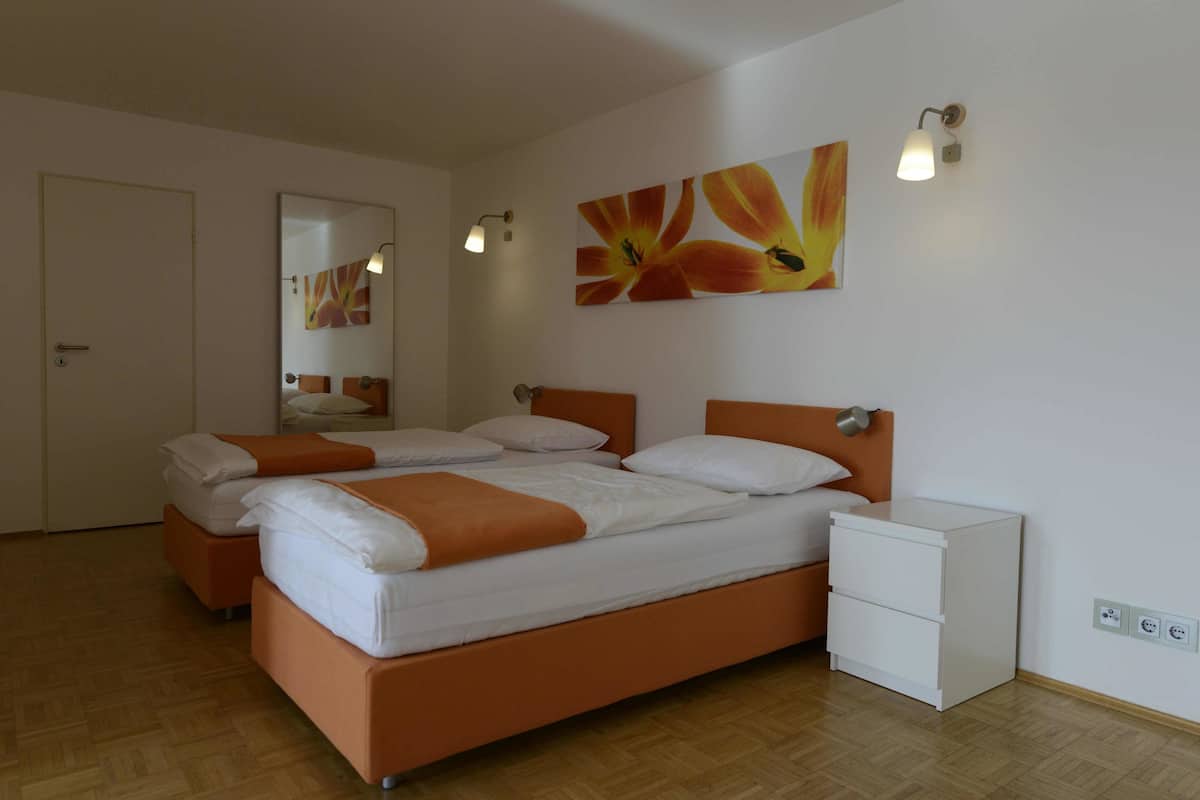 A bedroom with a bed, two bedside tables, a nightstand, a mirror, and wall art.