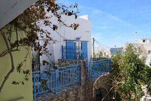 A narrow street with a white building and a blue gate. - Aratos Hotel (Paros)