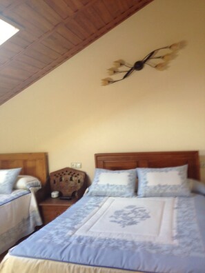 Un dormitorio con dos camas, cabeceros de madera, techo de madera y una lámpara de pared.