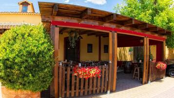 A restaurant with outdoor seating, a covered patio, and a brick pathway.