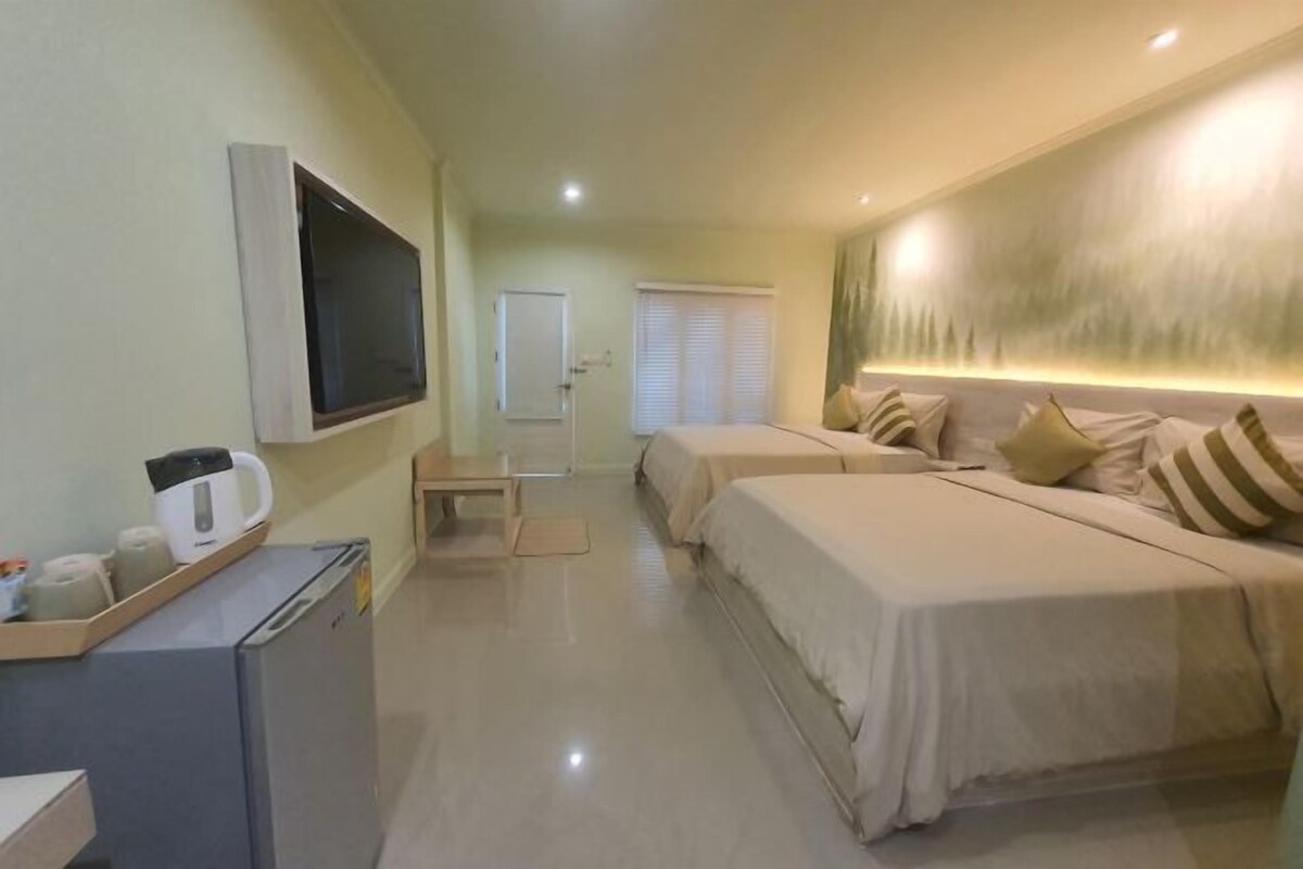 A hotel room with two beds, a TV, a refrigerator, and a window with blinds.