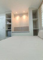 Un dormitorio con cama, estanterías empotradas, microondas y un refrigerador pequeño.