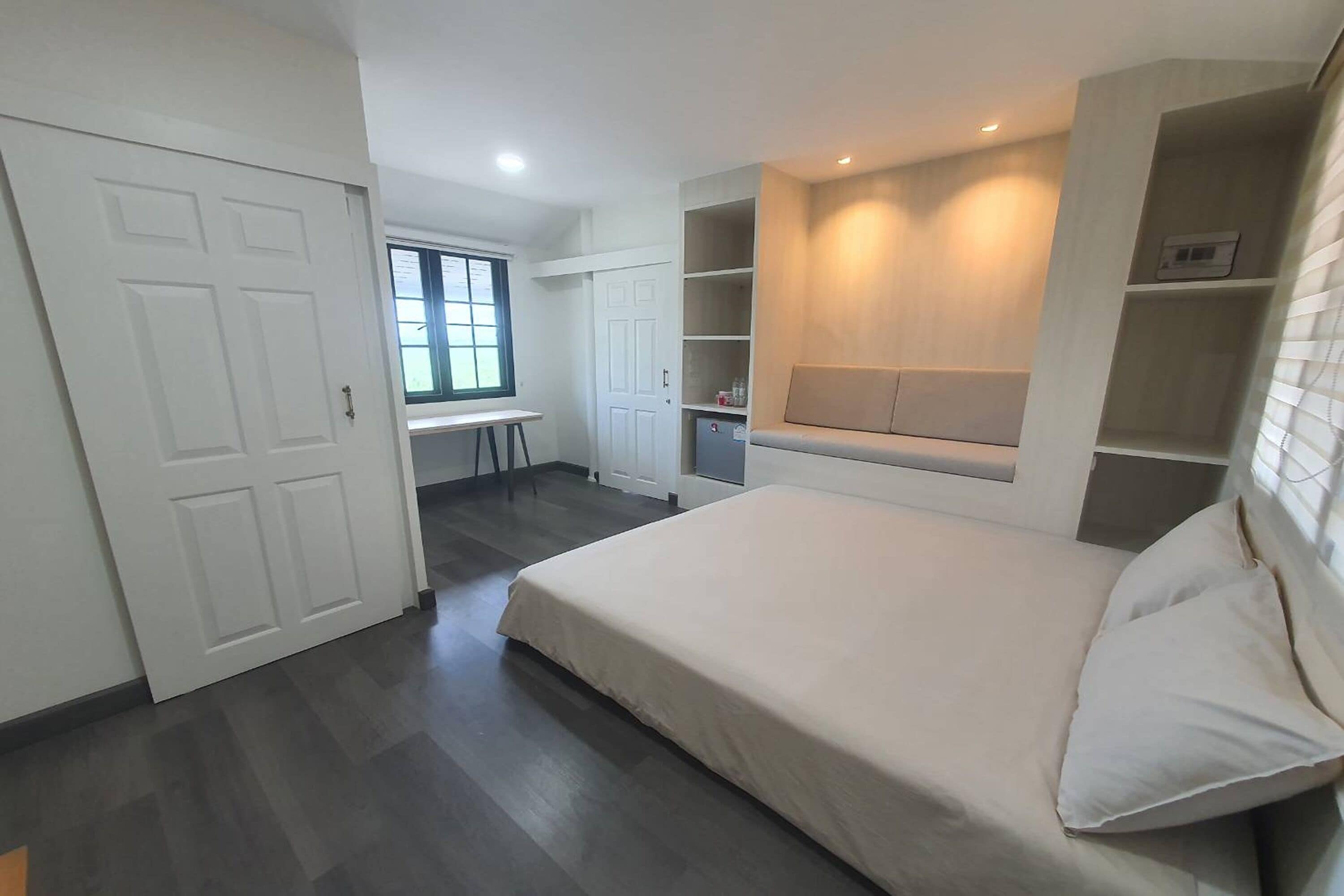 Un dormitorio con cama, estanterías empotradas, un escritorio y una ventana.