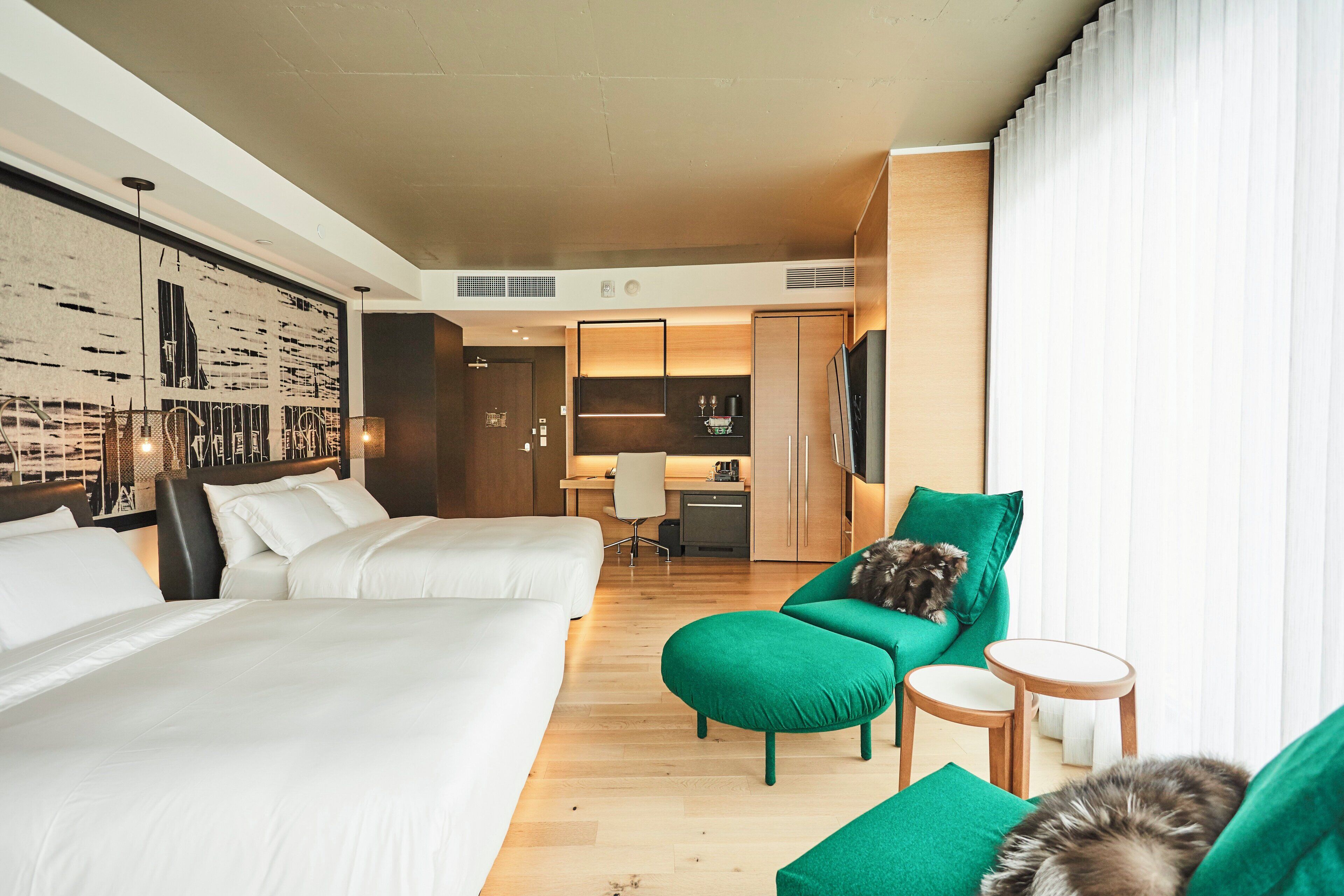 A hotel room with two beds, a green sofa, a small table, and a TV.