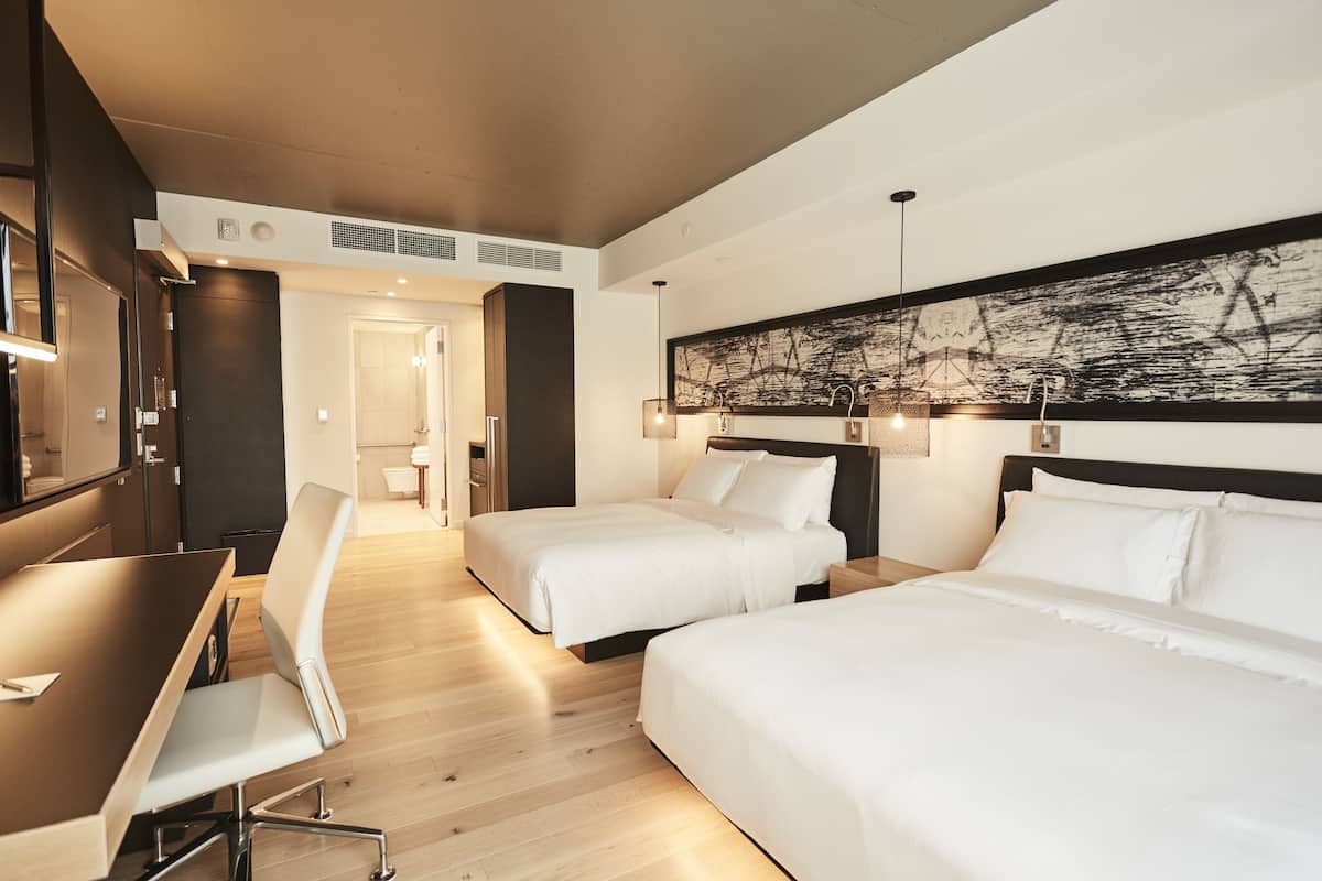 A hotel room with two beds, a desk, and a chair.