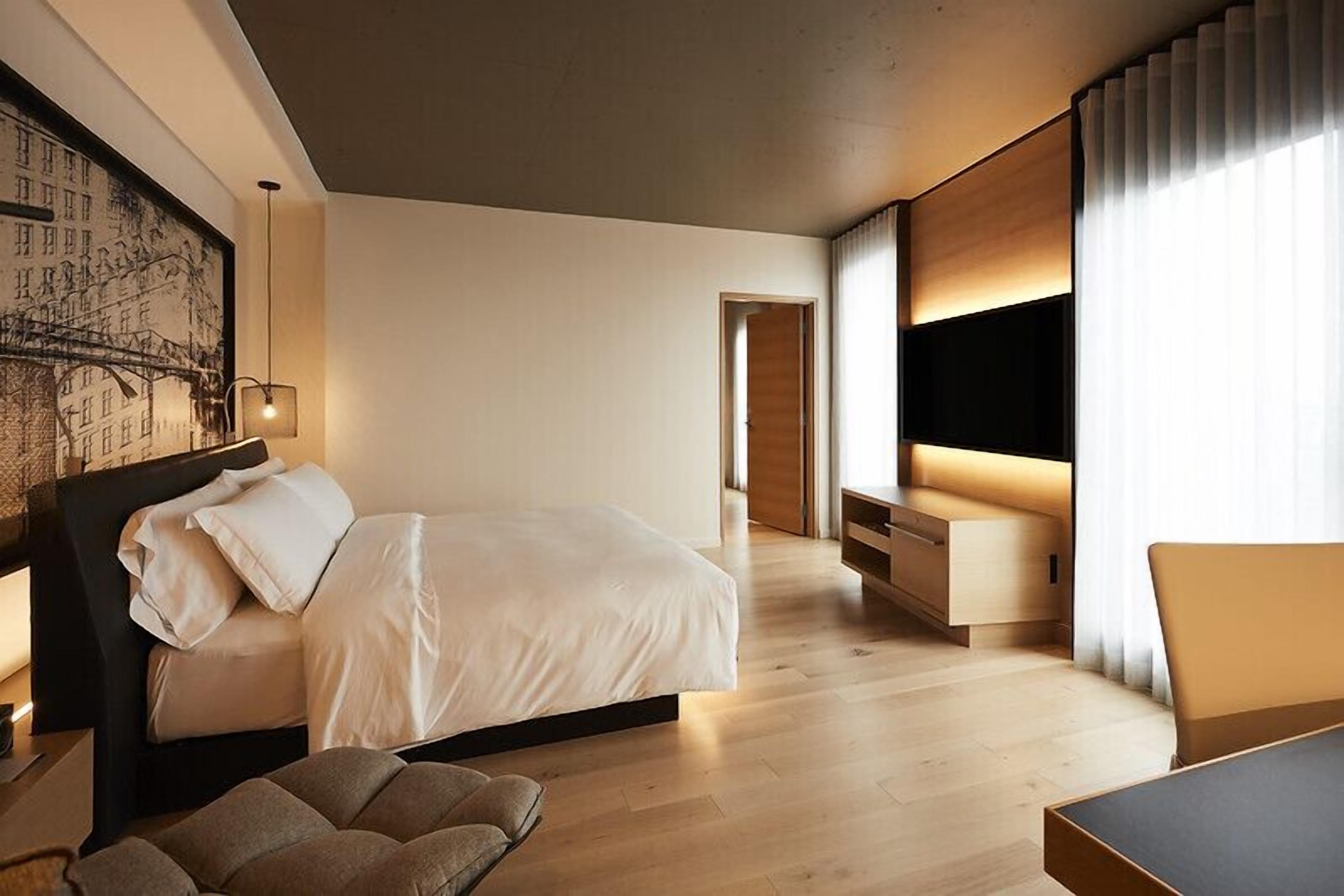 Una habitación de hotel moderna con una cama grande, un escritorio y un televisor.