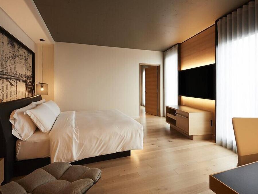 Una habitación de hotel moderna con una cama grande, un escritorio y un televisor.
