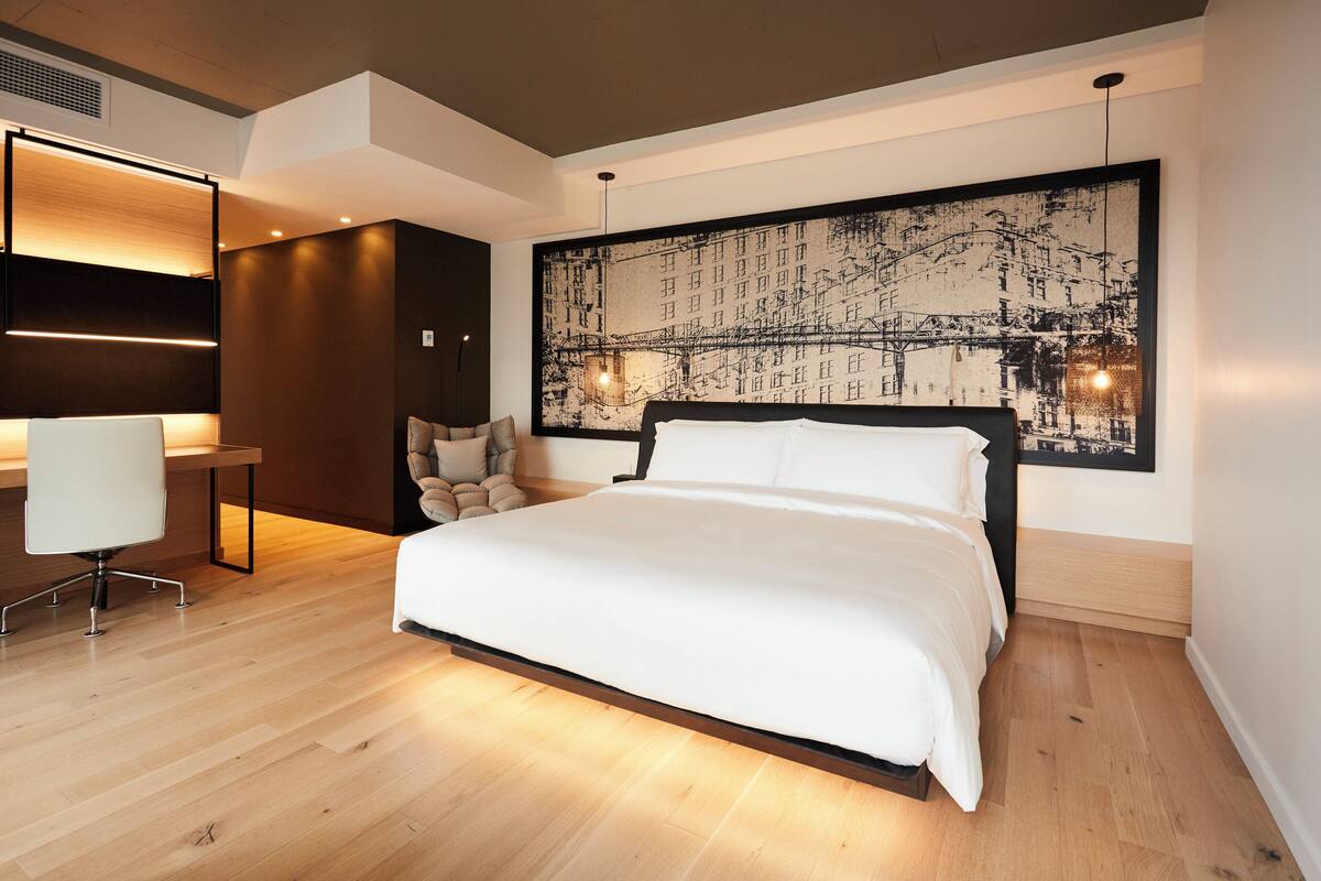 A modern bedroom with a large bed, a desk, and a chair.