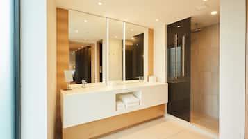 A modern bathroom with a large mirror, a sink, and a shower area.