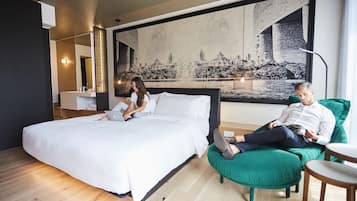 A modern hotel room with a large bed, a green armchair, and a cityscape mural on the wall.