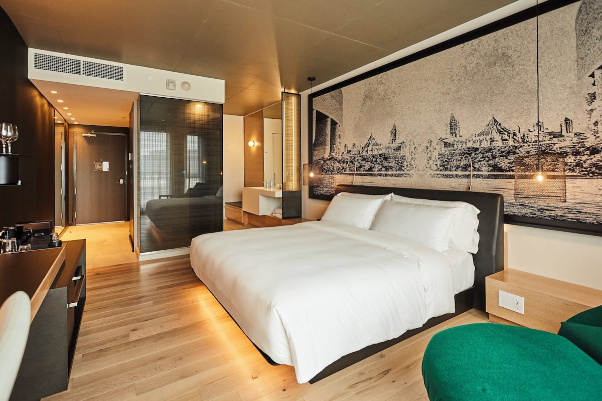 A modern hotel room with a large bed, a desk, and a seating area.