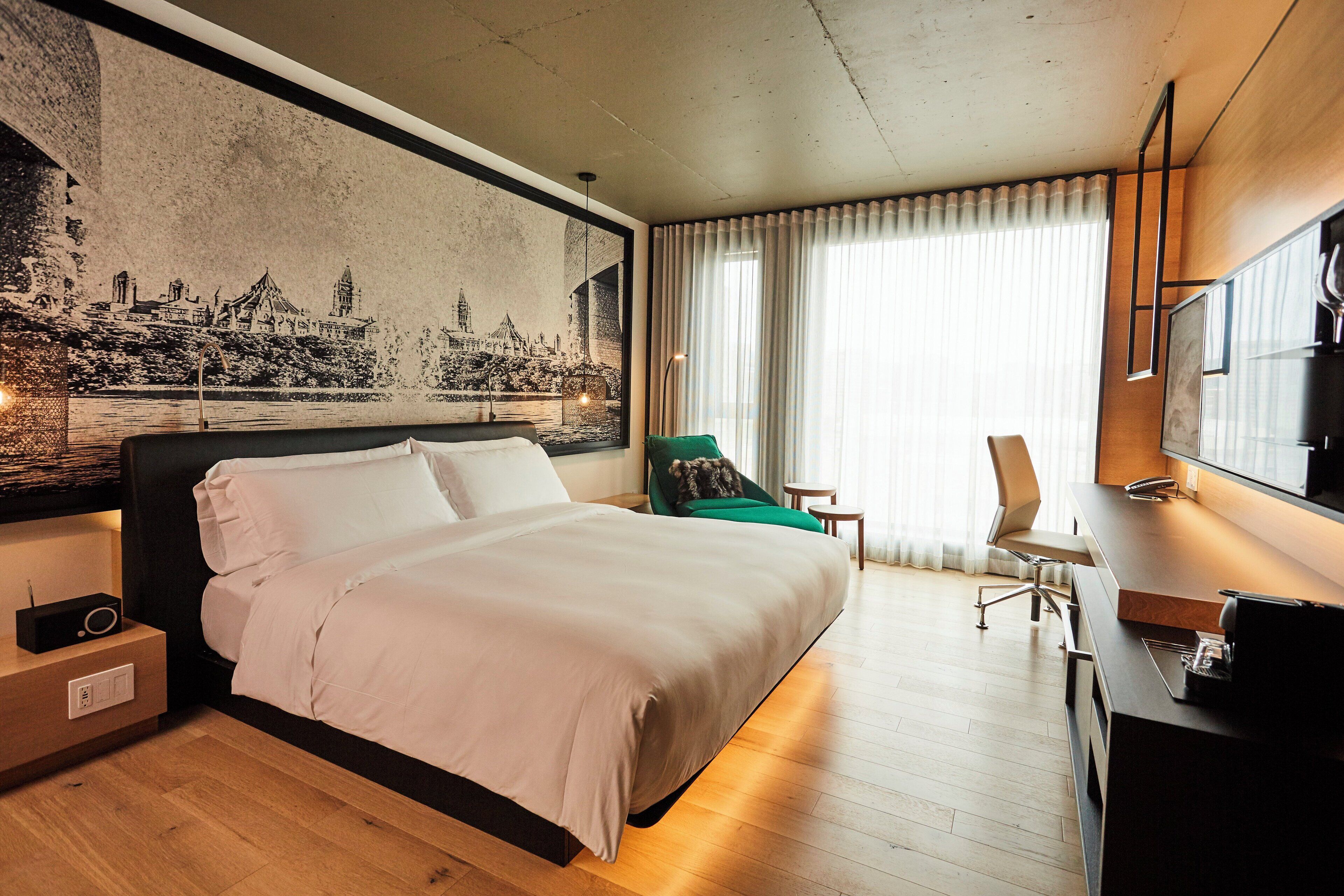 A hotel room with a large bed, a desk, a chair, and a television.